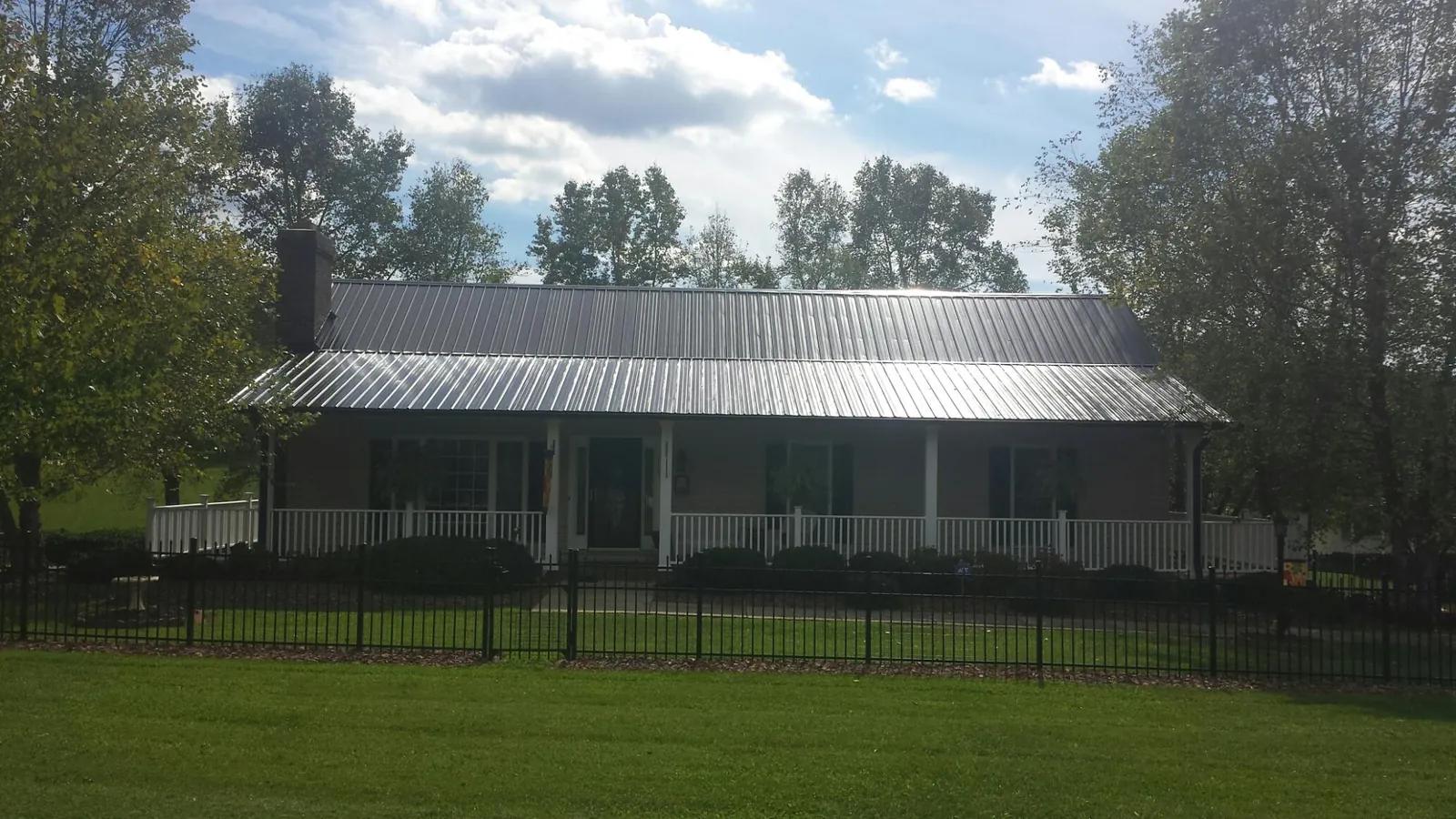 Gray metal roof on a brick ranch with a full width front porch — Gutter Guard Installation work by our crew in Dayton